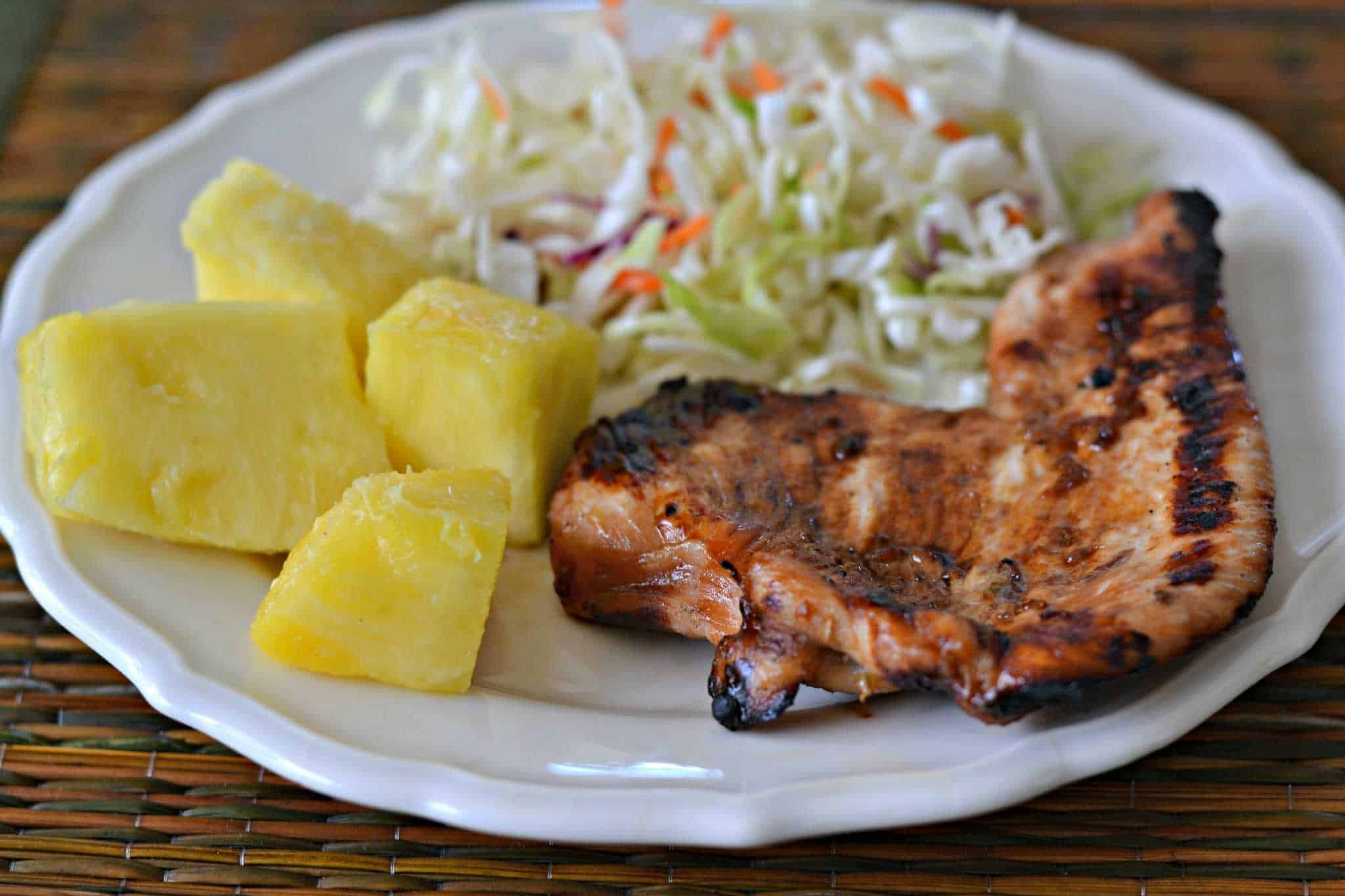 Teriyaki Turkey on a plate with pineapple chunks and coleslaw.