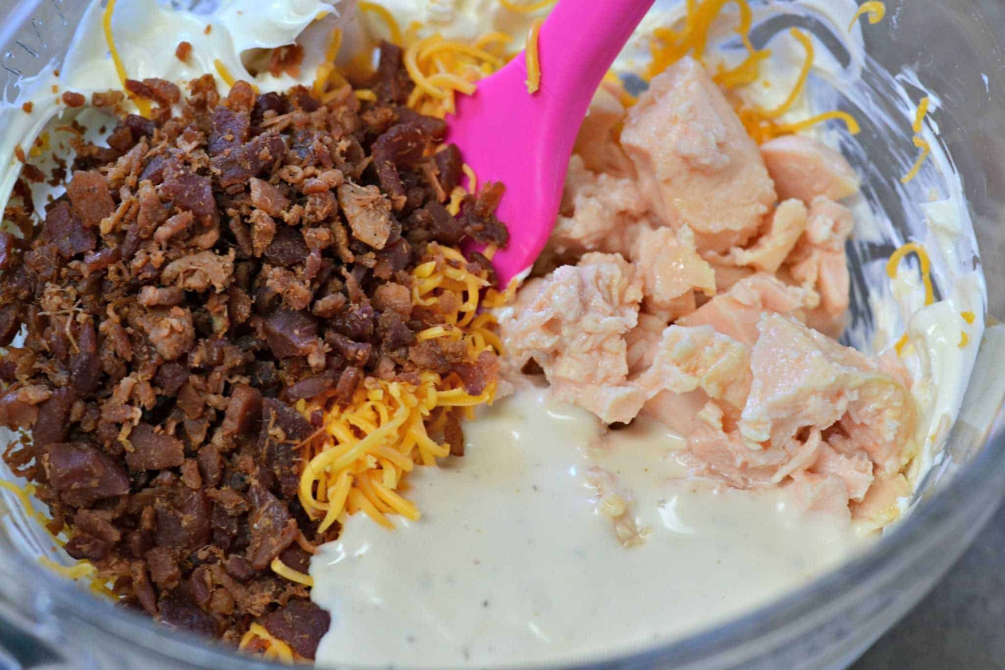 chicken, bacon, and cheese being mixed together