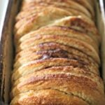 Baked loaf of cinnamon bread in a stoneware pan.
