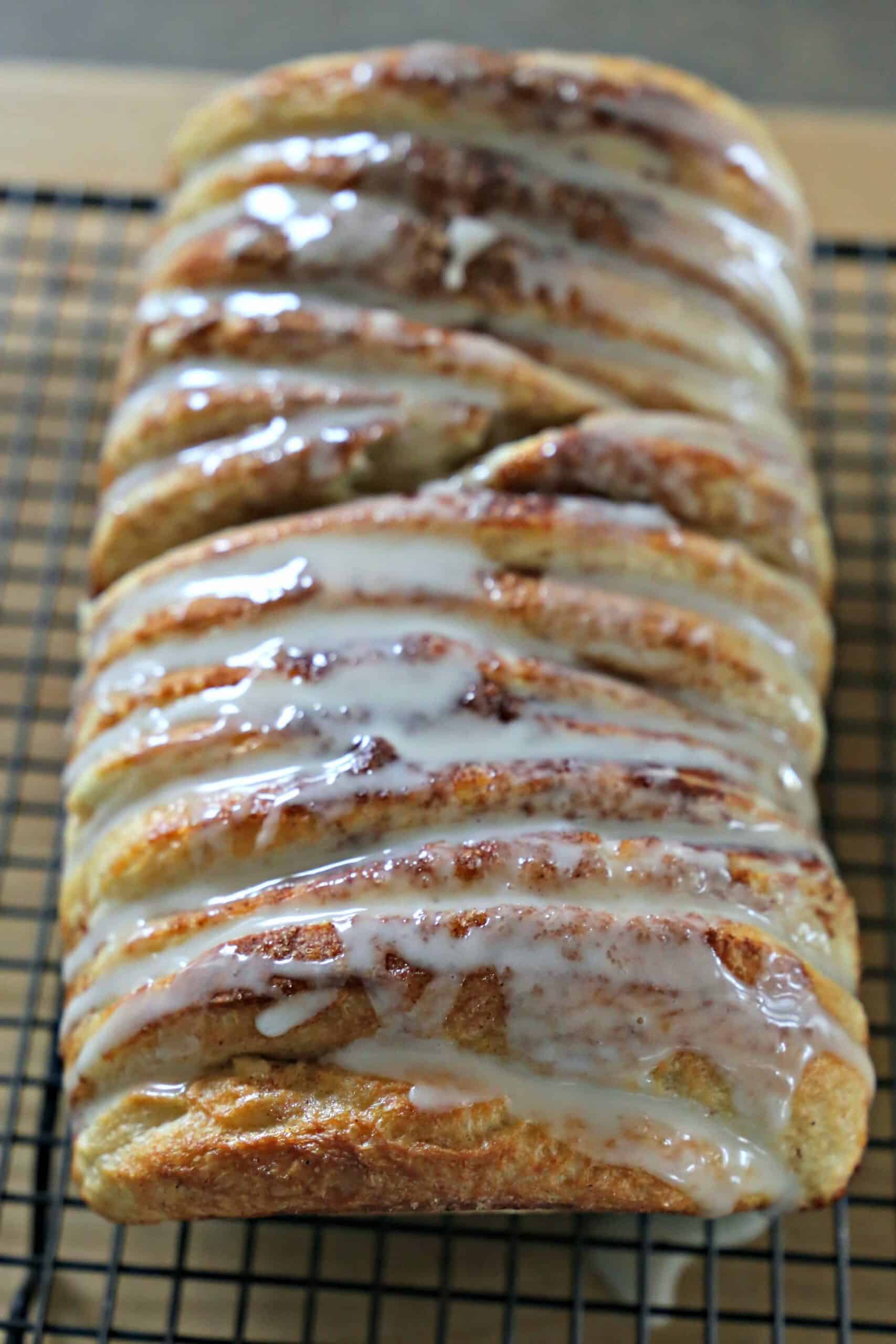 Glazed cinnamon bread on a wire cooling rack.