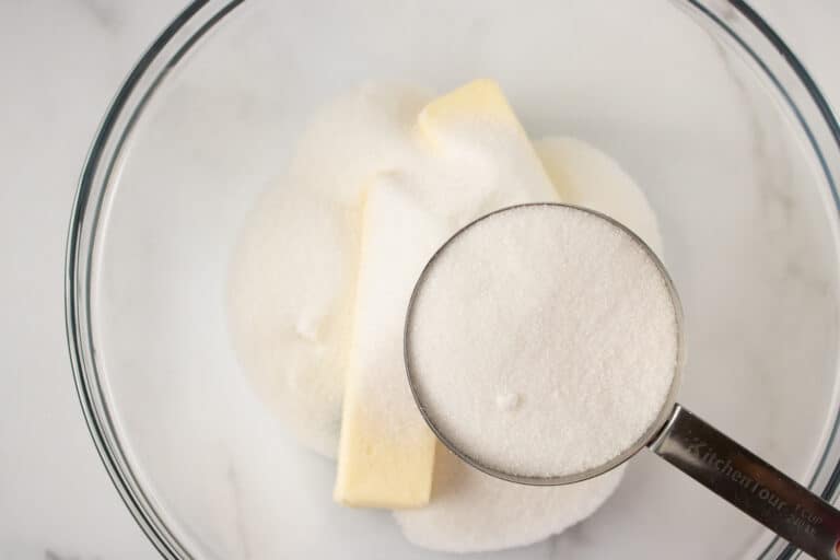 adding sugar to a bowl with butter in it
