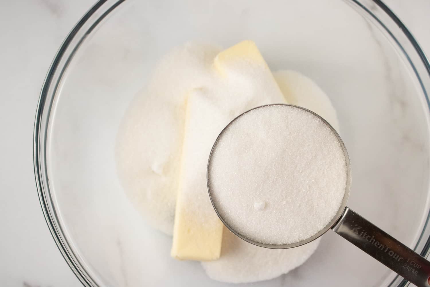 adding sugar to a bowl with butter in it