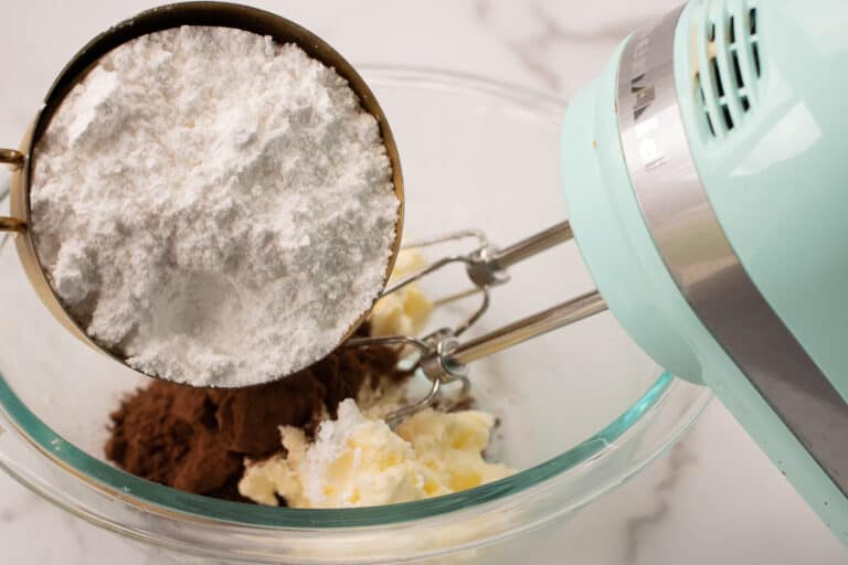adding powdered sugar to butter and cocoa powder