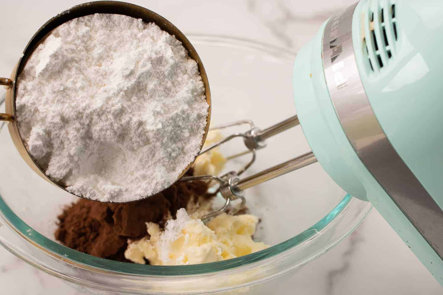 adding powdered sugar to butter and cocoa powder