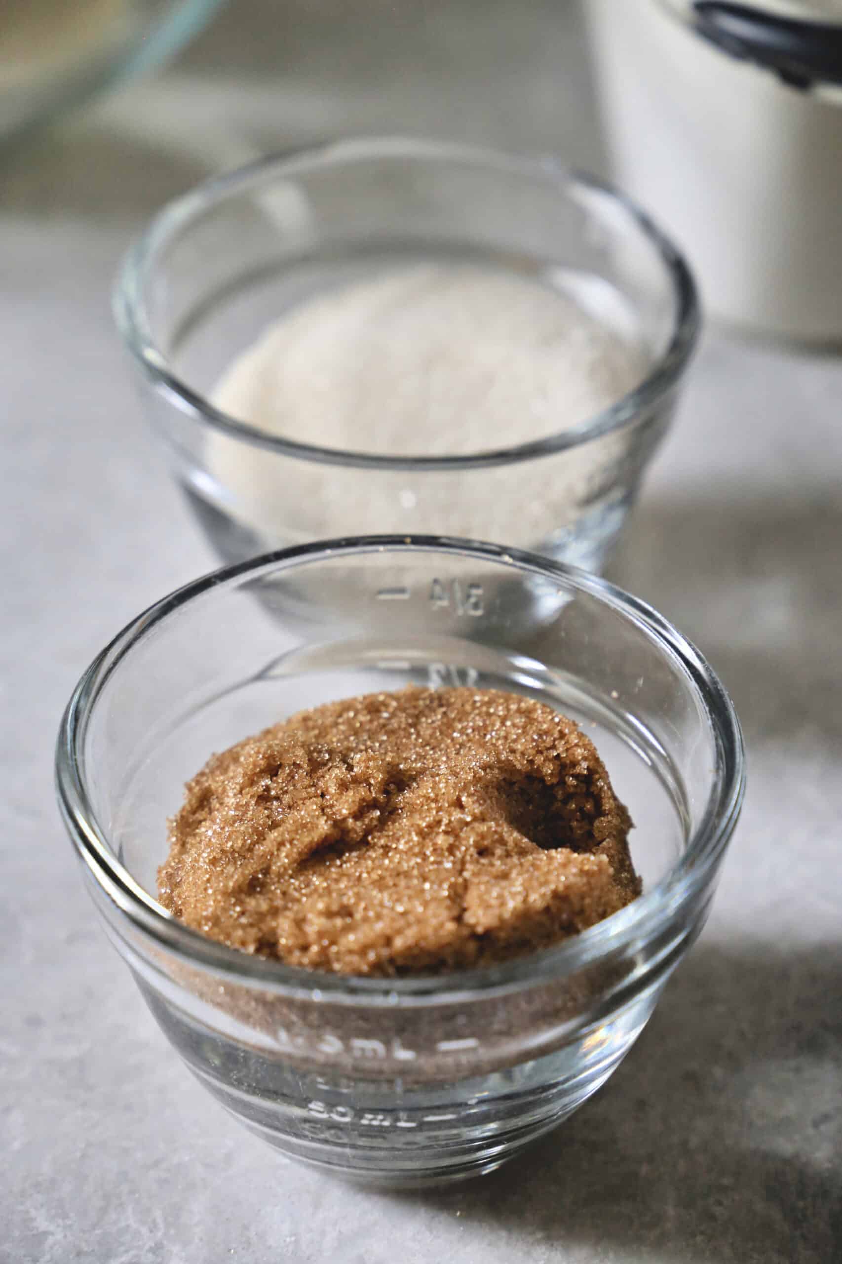 Two small glass bowls with sugar and brown sugar.