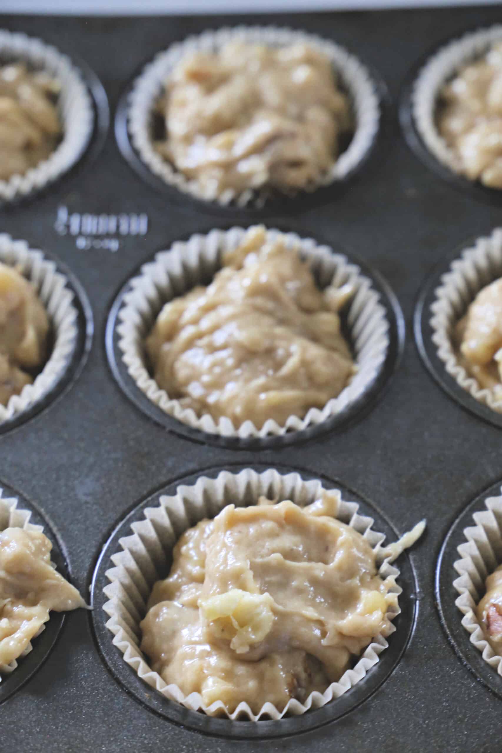 Banana nut muffin batter in muffin cups in a baking tin before being baked.