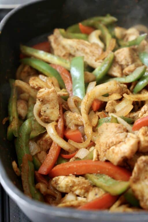 skillet with fajitas made with chicken, onions, and bell peppers