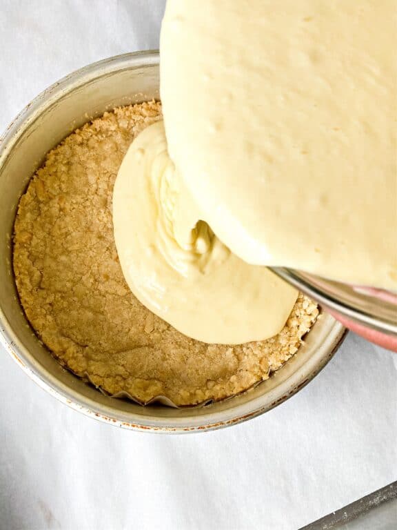 pouring cheesecake batter into crust