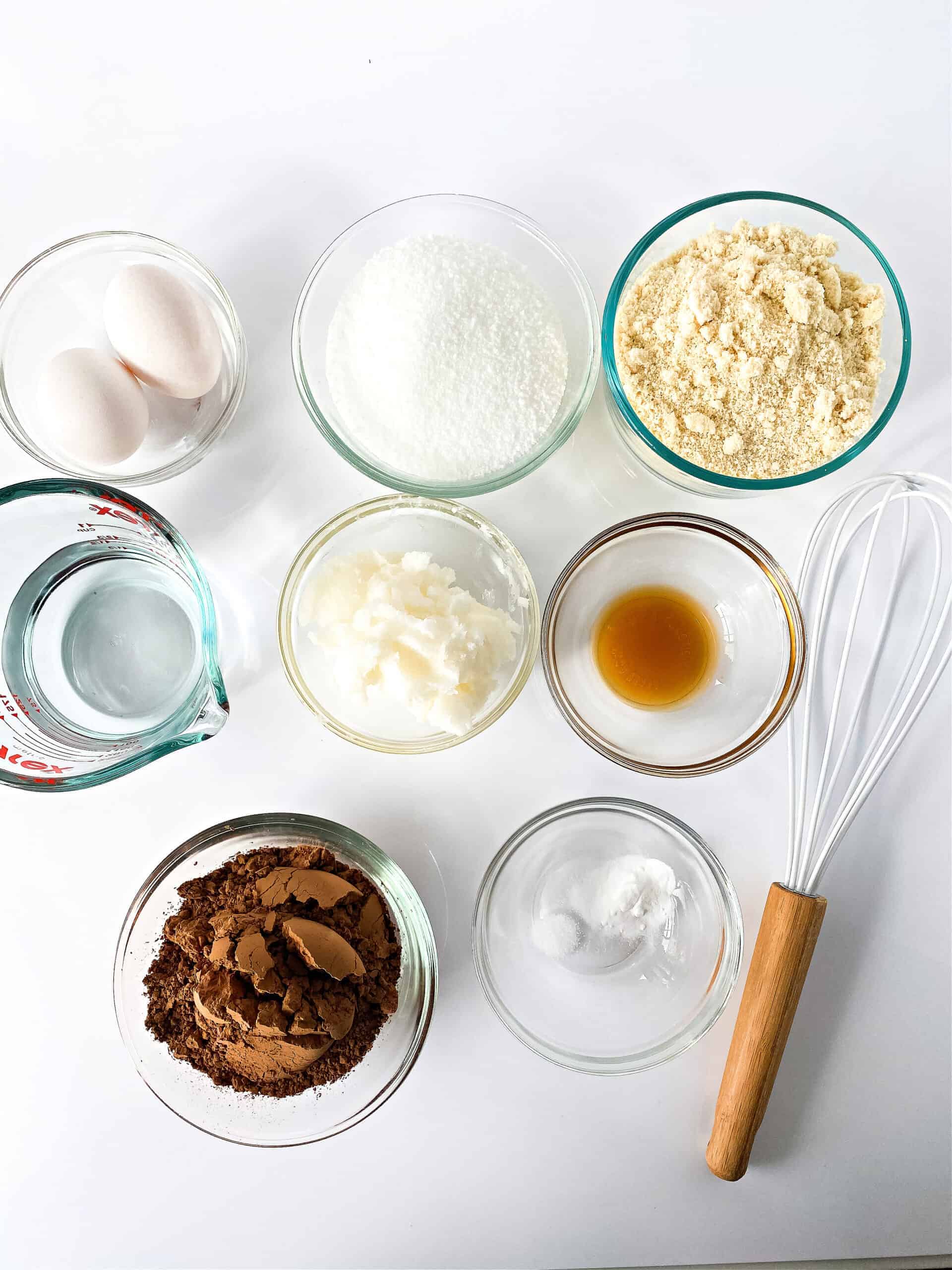 Bowls filled with almond flour, cocoa powder, stevia, coconut oil, vanilla, and eggs.