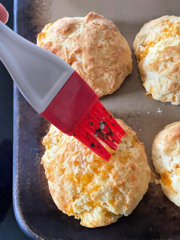 brushing cheddar biscuits with butter and herbs