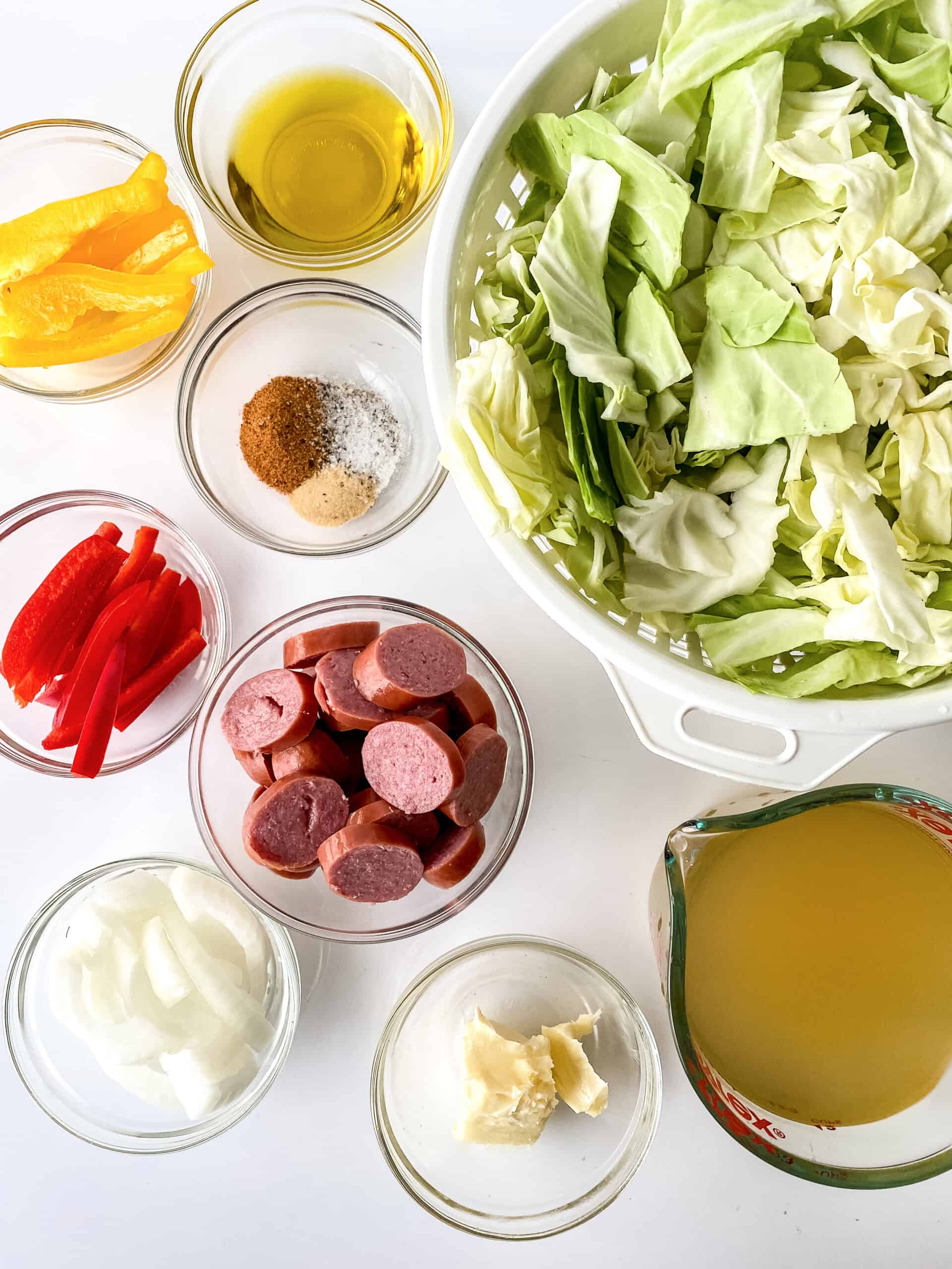 Cabbage, sausage, bell peppers, and onions in bowls.