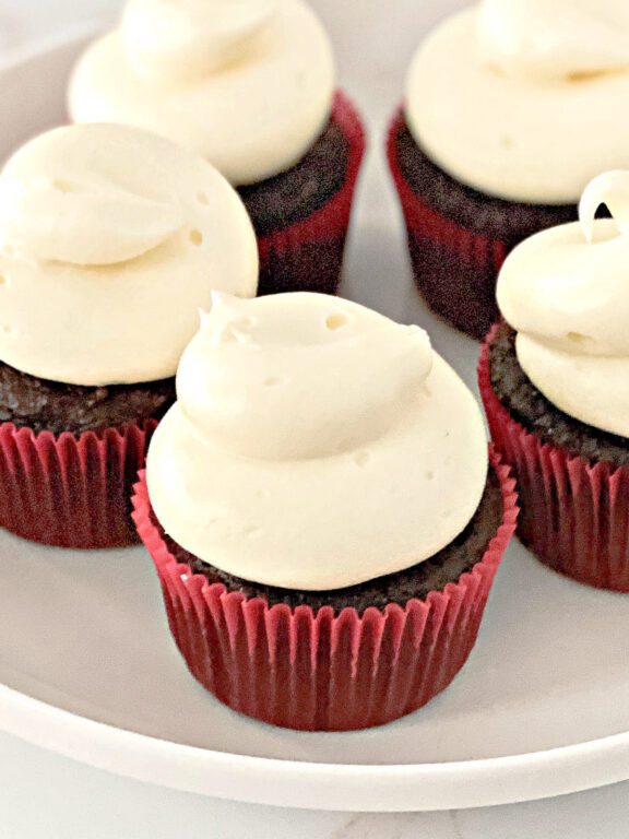 chocolate cupcakes decorated with cream cheese frosting on a plate