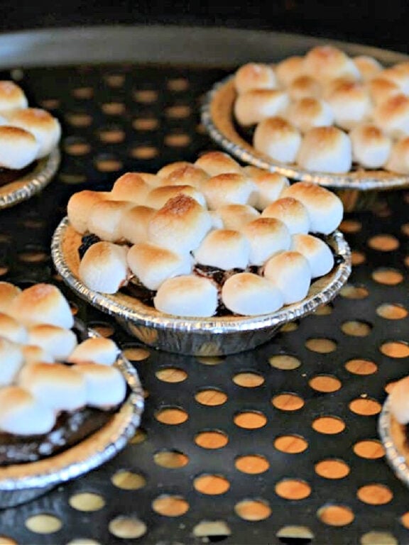 Toasting marshmallows to make miniature s'mores pies - yum! toasting marshmallows on top of a chocolate pie