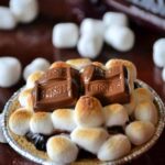 Miniature s'mores pie made with a graham cracker crust, chocolate pudding, and topped with miniature marshmallows and a chocolate bar.