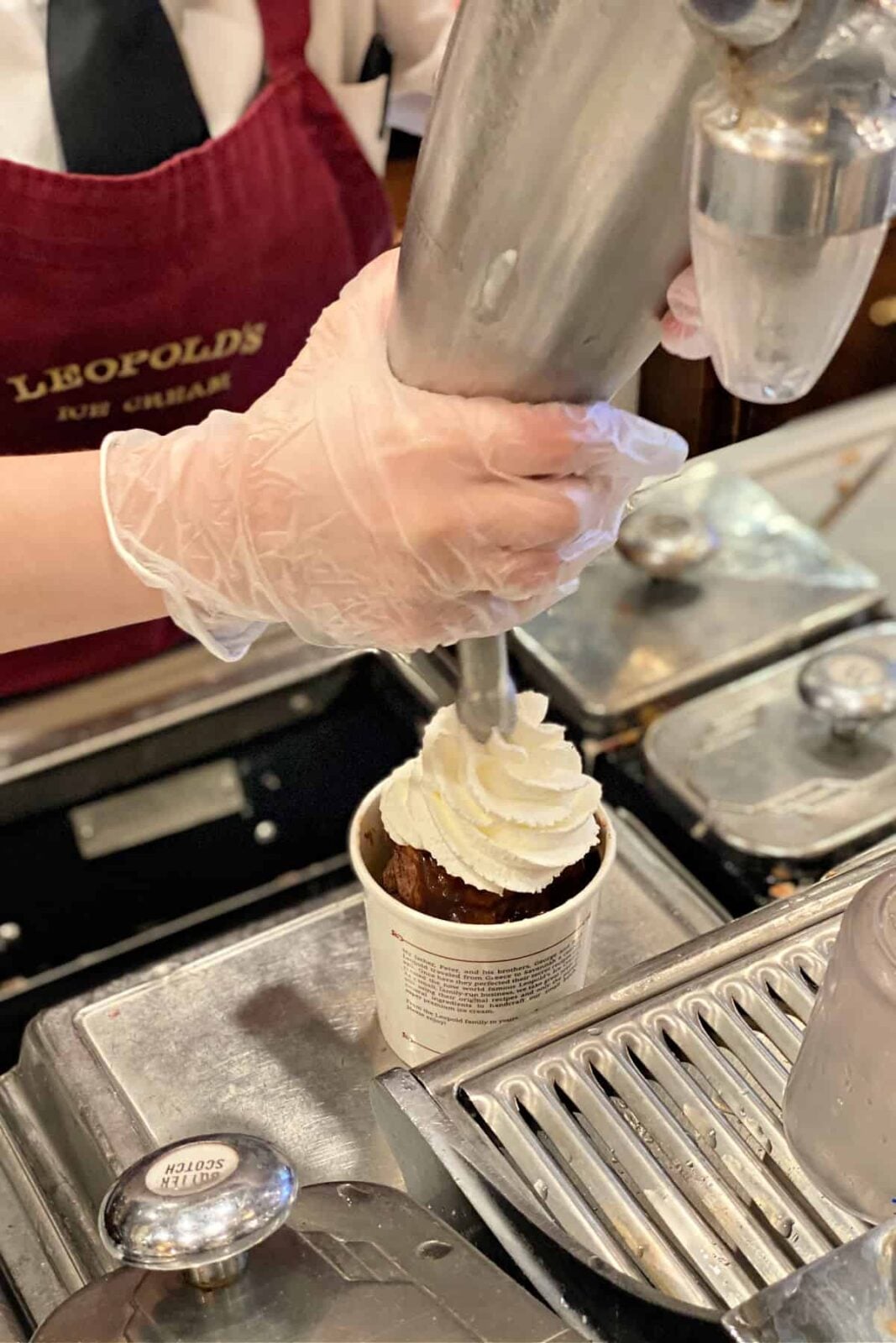 Piping whipped cream on top of a brownie sundae.