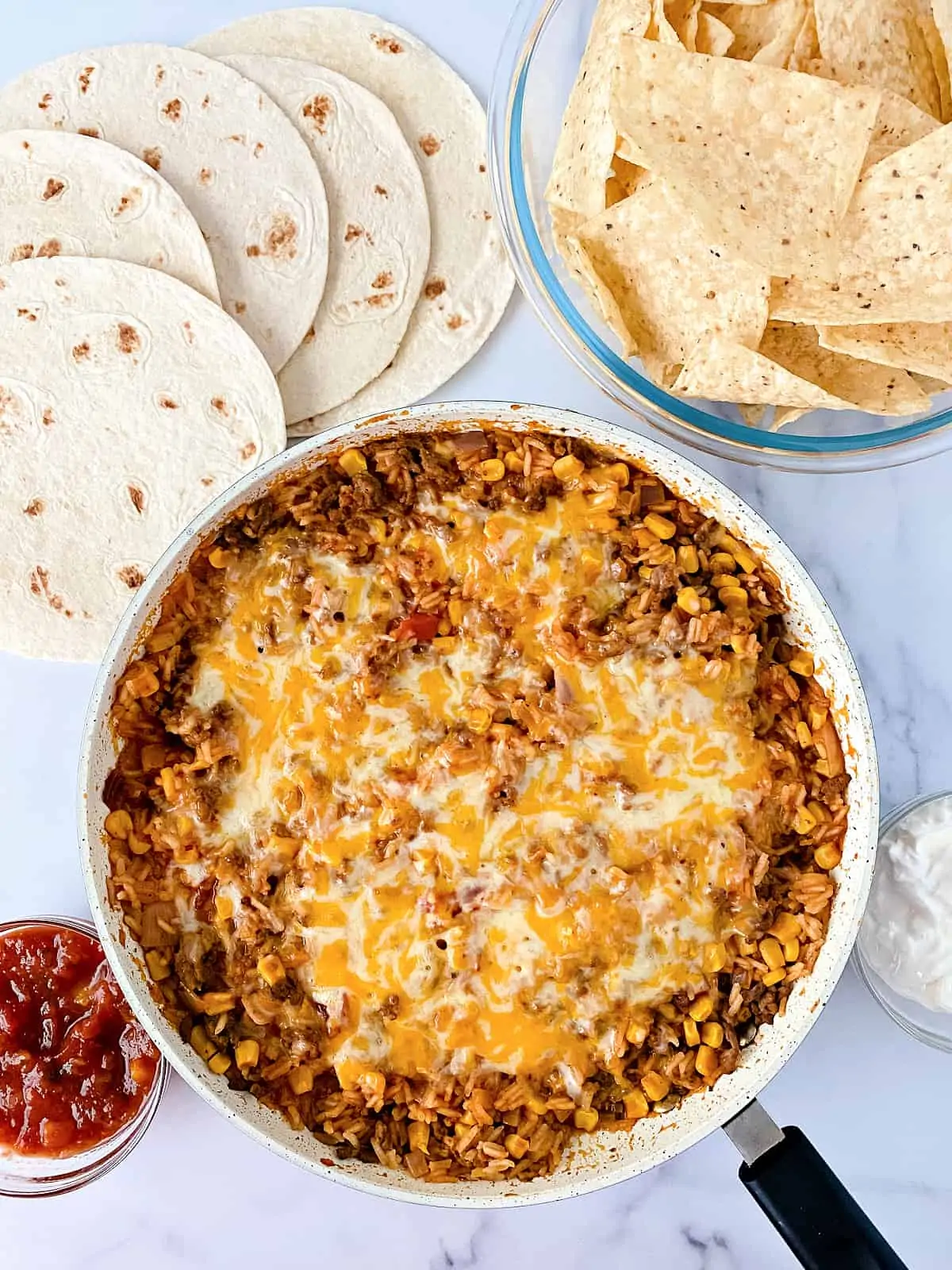 Mexican Casserole in a pan served with tortillas, and tortilla chips.