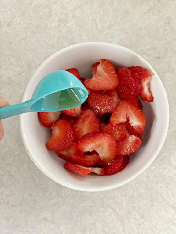 pouring maple syrup over strawberries