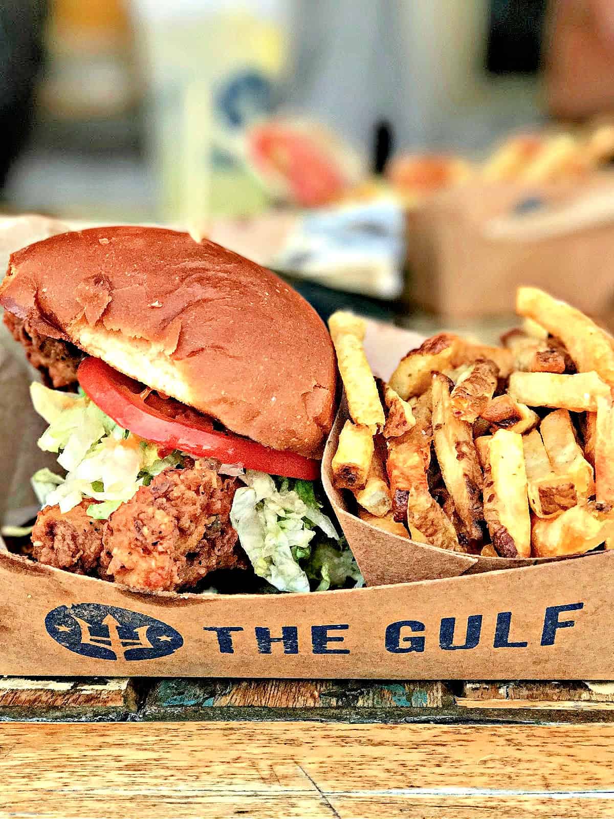Fried fish sandwich with lettuce and tomato served with hand-cut French fries at The Gulf in Orange Beach.