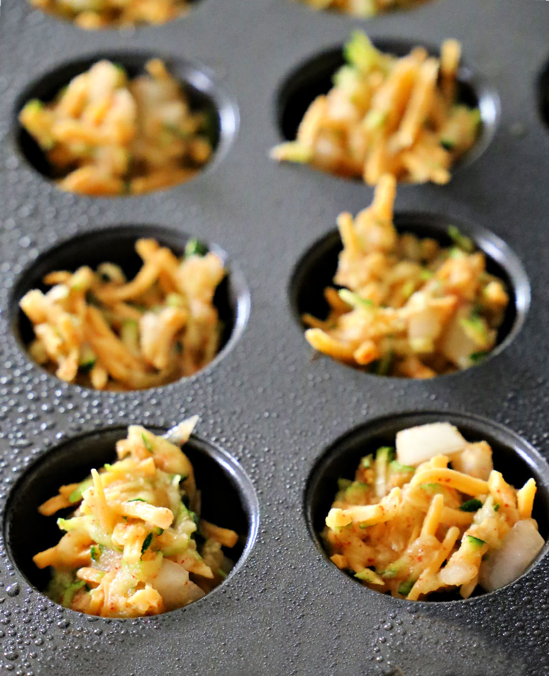 unbaked zucchini tots in a muffin tin