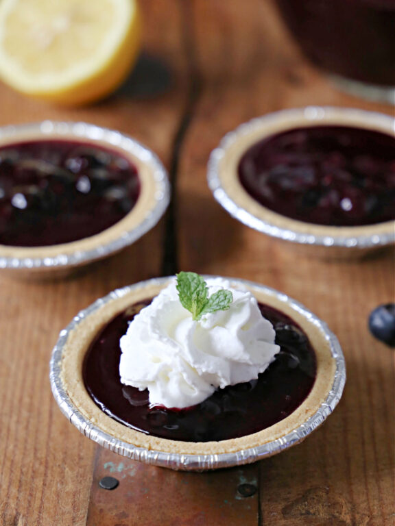 Miniature blueberry pies topped with whipped cream and mint