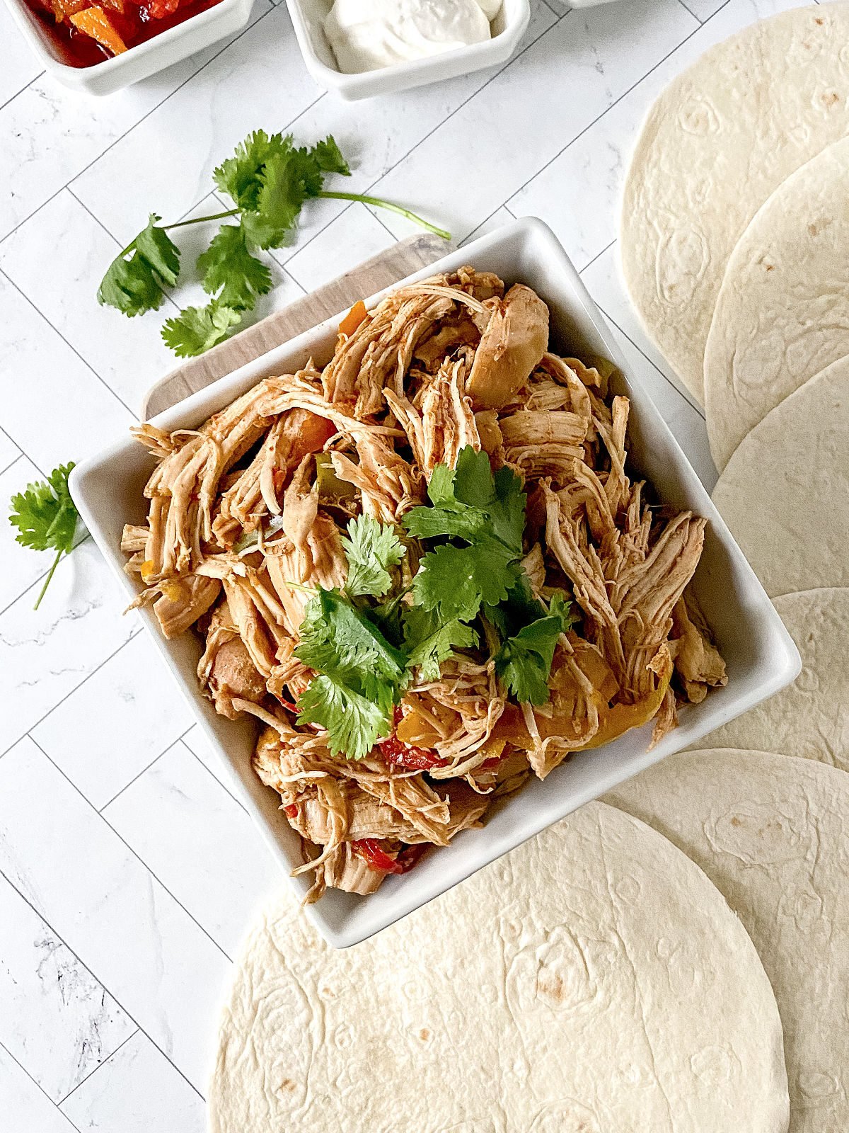 Bowl of shredded chicken topped with cilantro.