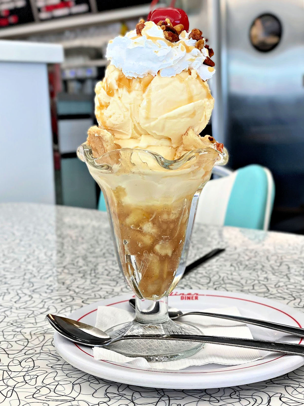 A large caramel apple sundae topped with whipped cream and a cherry.