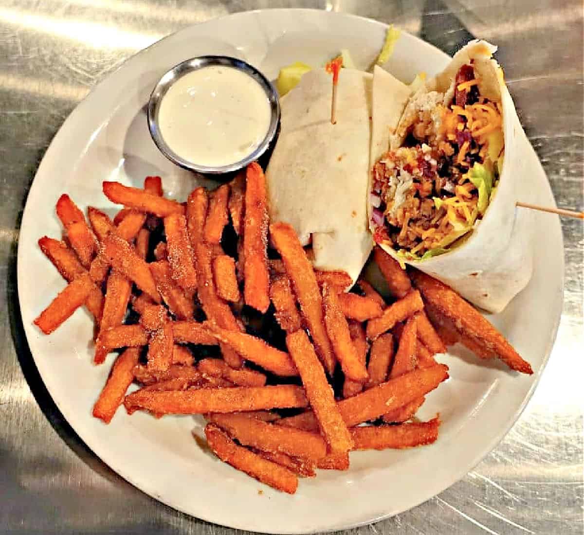Plate with chicken wrap and side of sweet potato French fries.