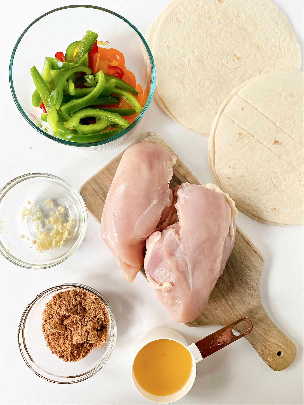 Raw chicken, fajita seasoning, sliced bell peppers, and tortillas.
