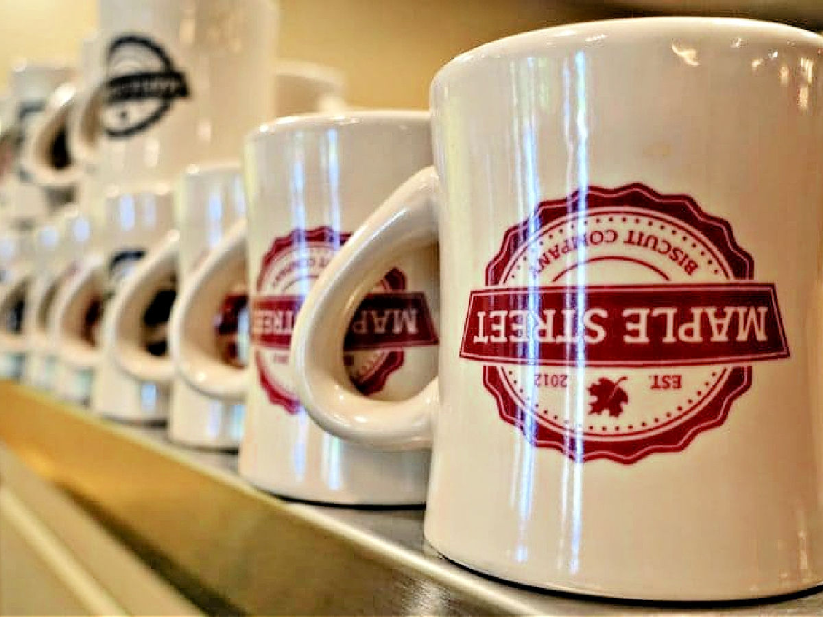 Row of Maple Street coffee mugs on a shelf.
