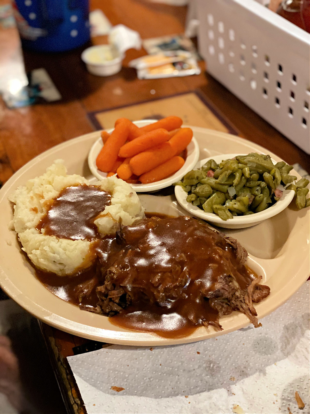 Plate of roast beef with mashed potatoes, carrots, and green beans.