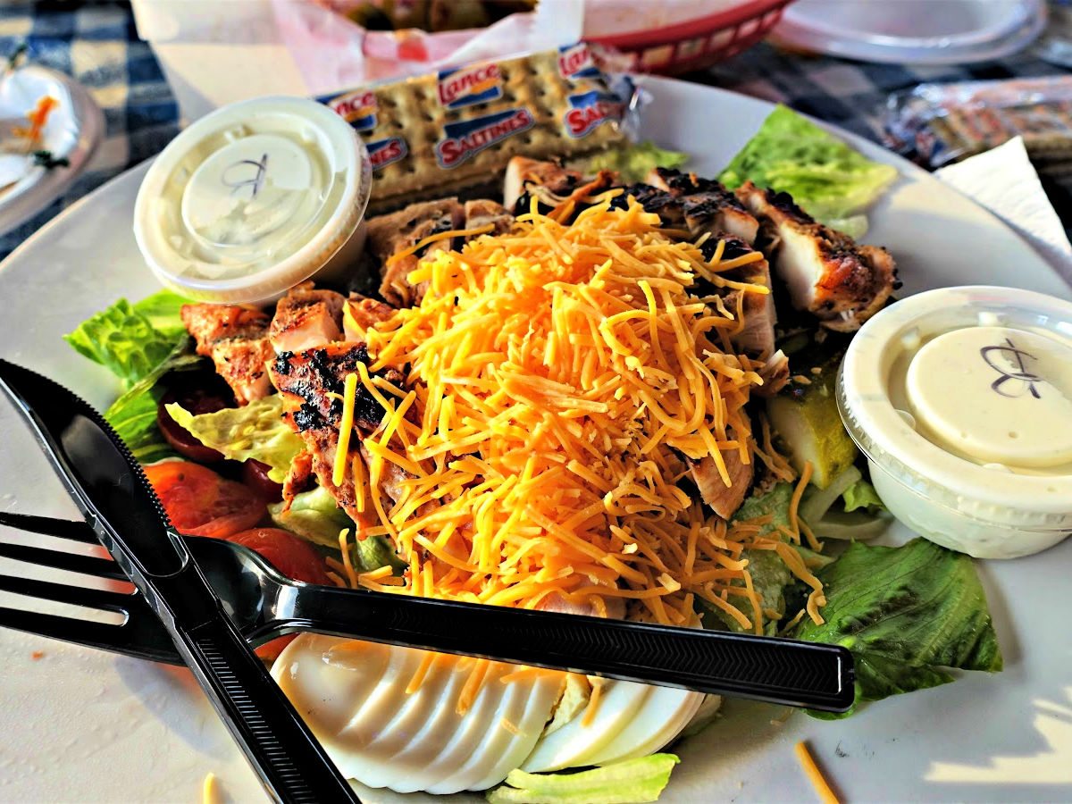 Where To Dine In the Shoals Deluxe Cobb salad with cheddar cheese, chicken, eggs, dressing, and packet of crackers.