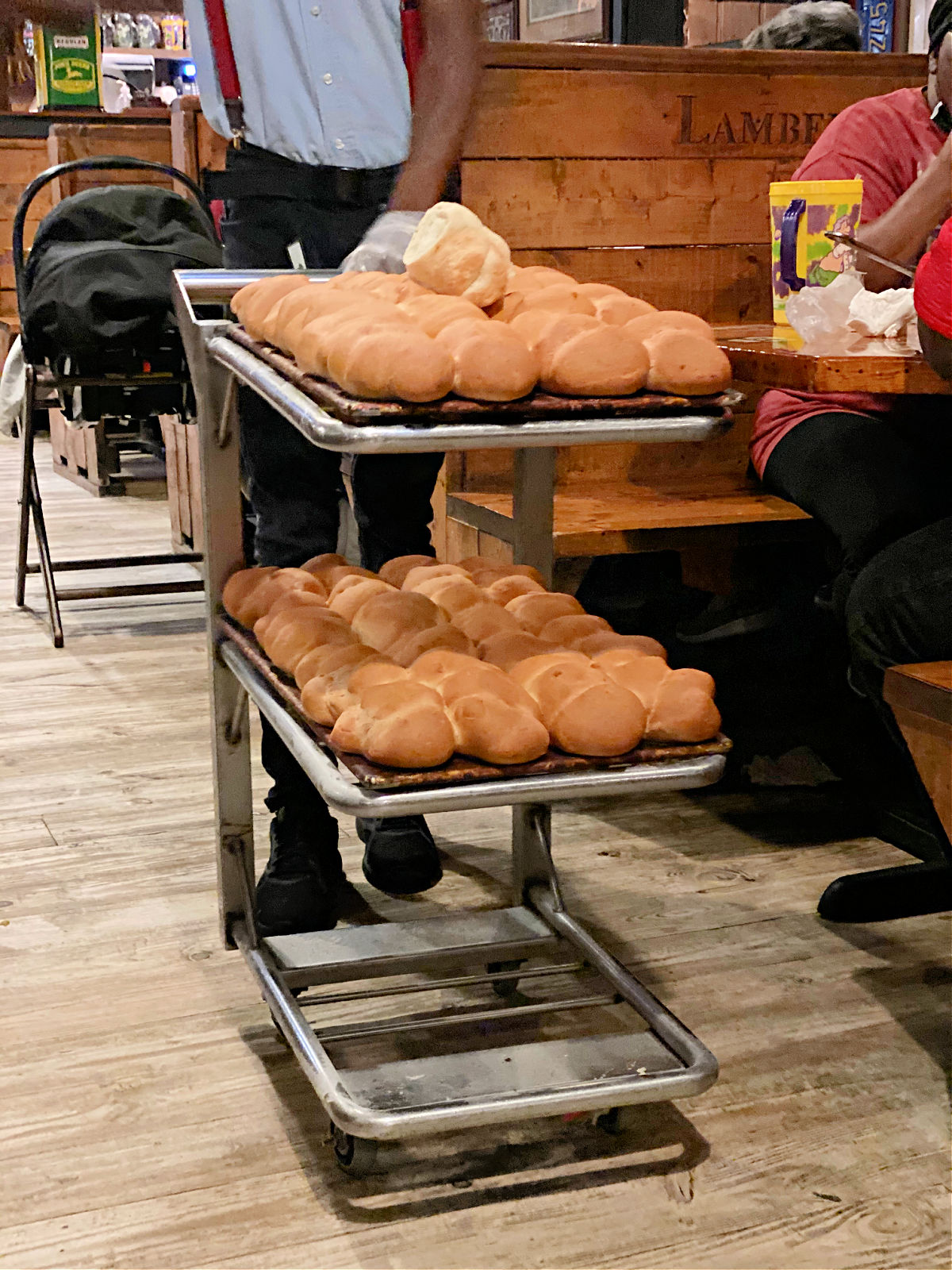 Man pushing a cart with dinner rolls.