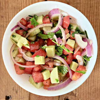 Bowl of tomato-cucumber salad with red onions.