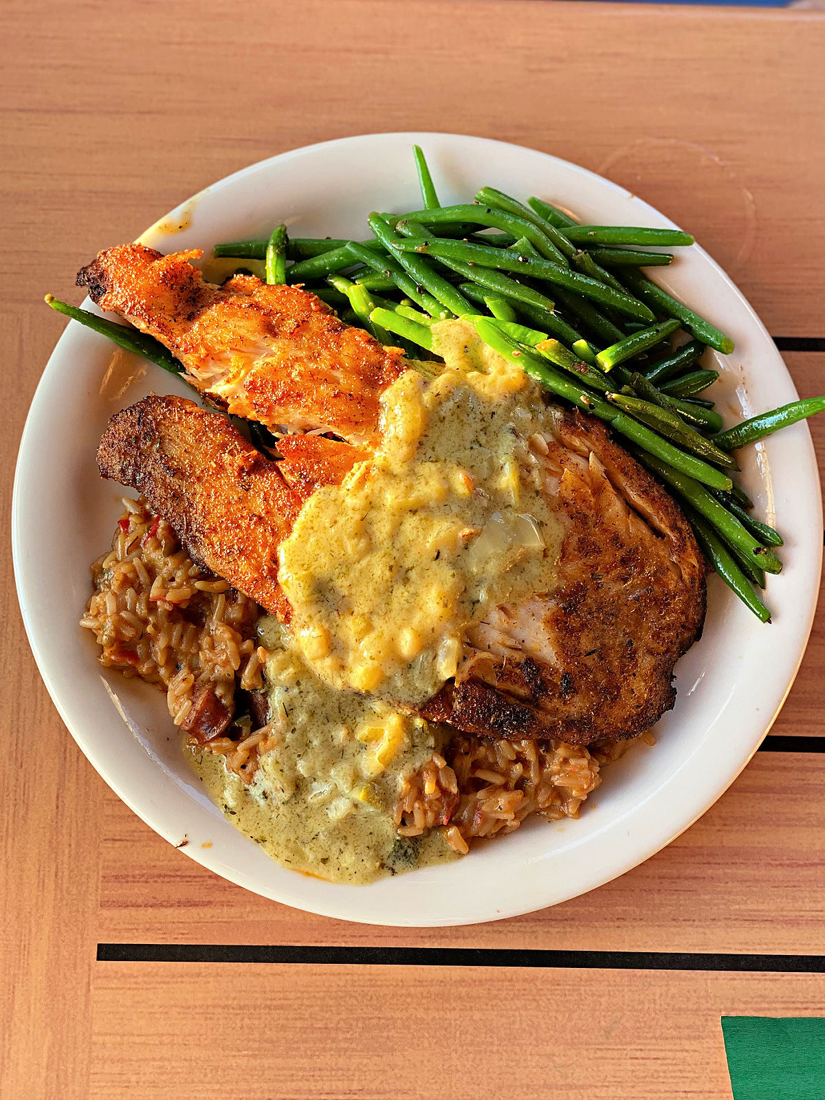 A plate with triple tail, green beans, and seasoned rice.