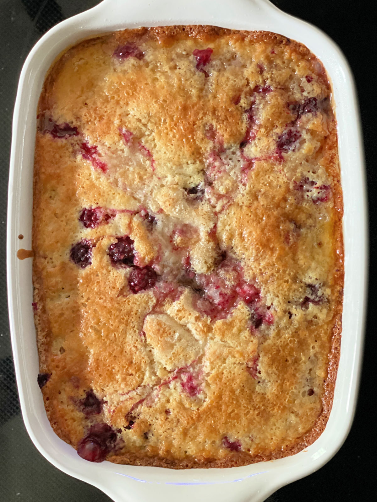 Baked blackberry cobbler in a white rectangle baking dish.