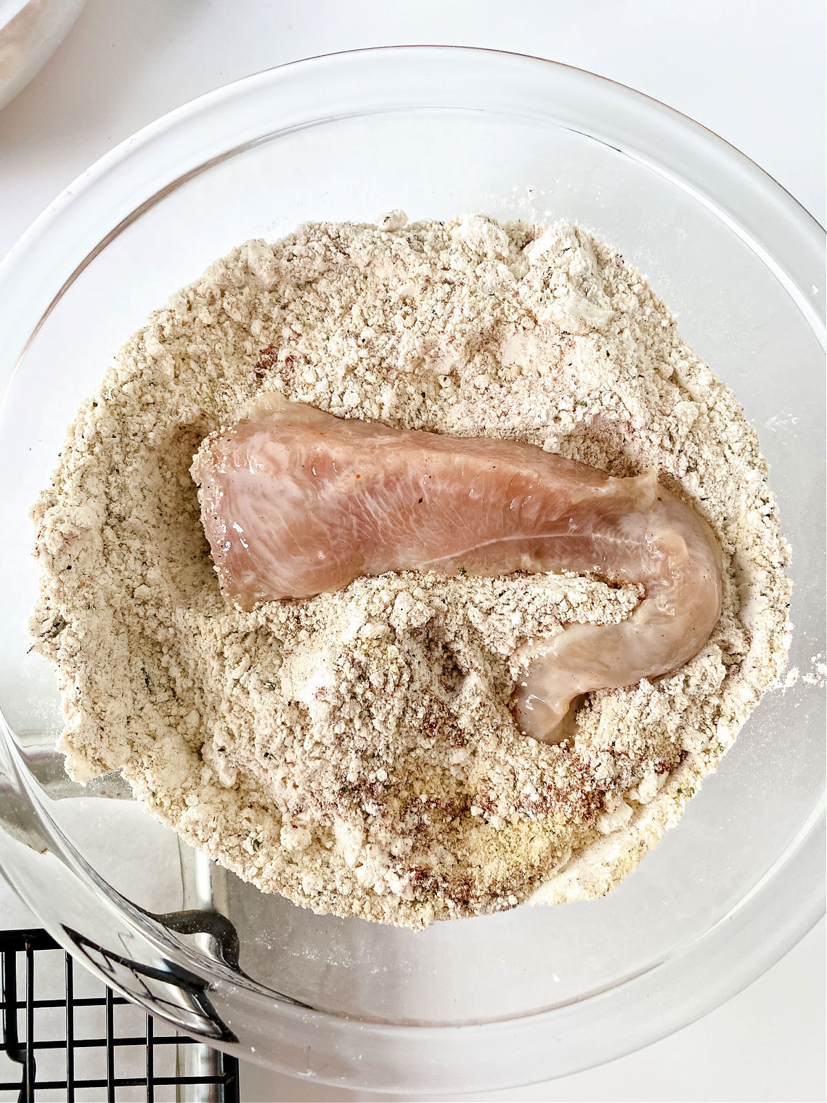 Dipping a chicken tender in seasoned breading.