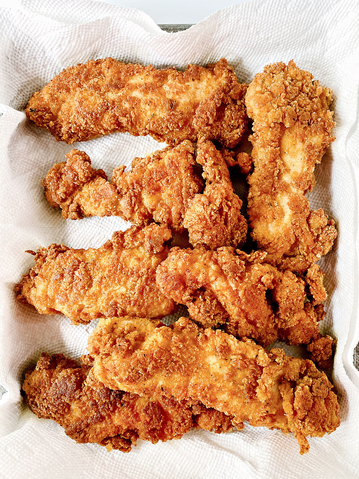 Chicken tenders draining on paper towels.