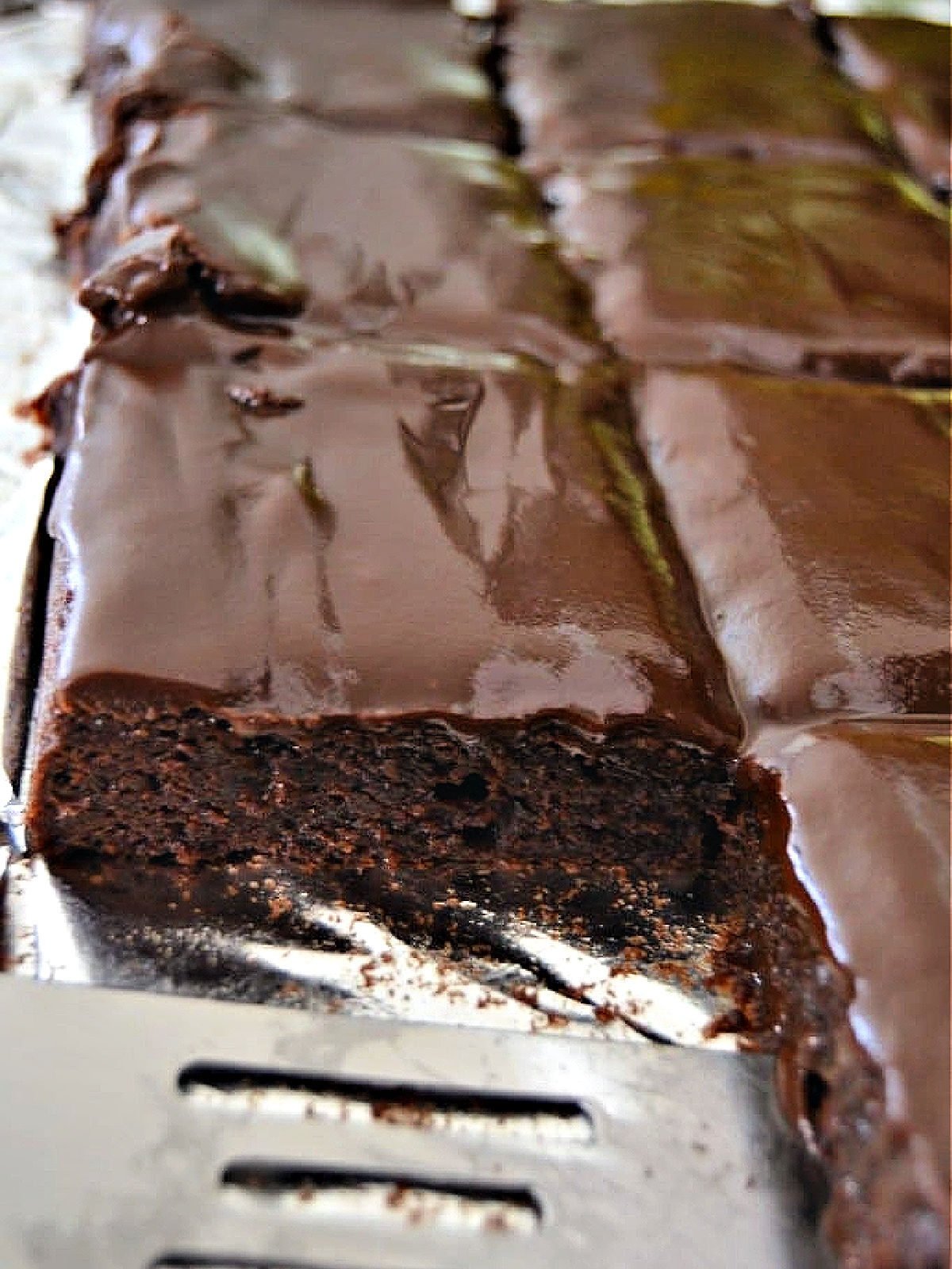 Sliced chocolate brownie cake and a metal spatula.