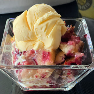 Glass bowl with blackberry cobbler and a scoop of vanilla ice cream.