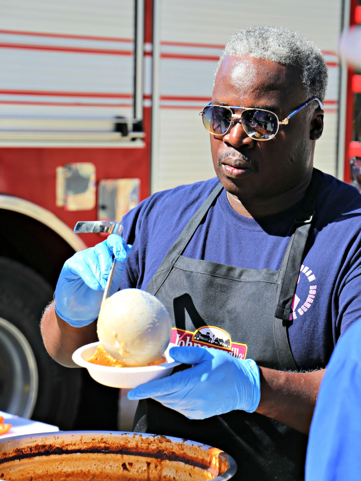 Fireman ladling chili into a bowl.
