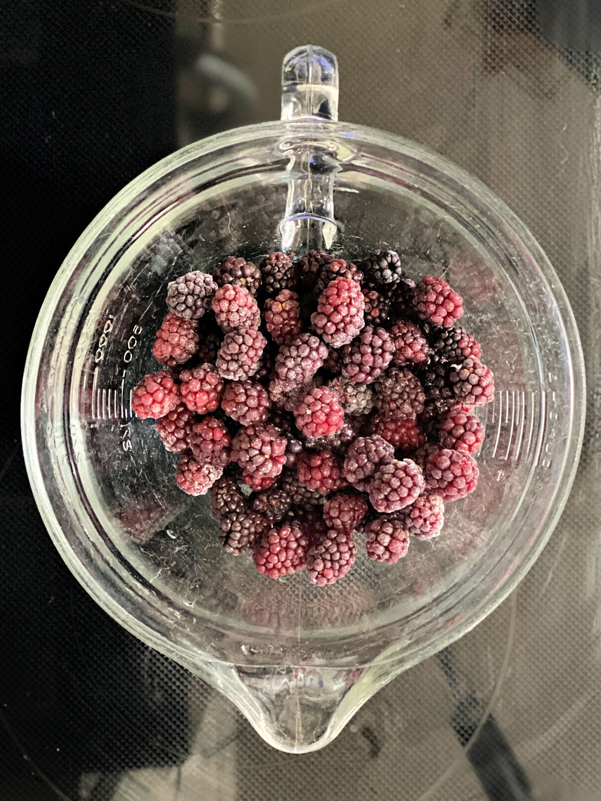 Frozen blackberries in a 2 quart glass measuring cup.
