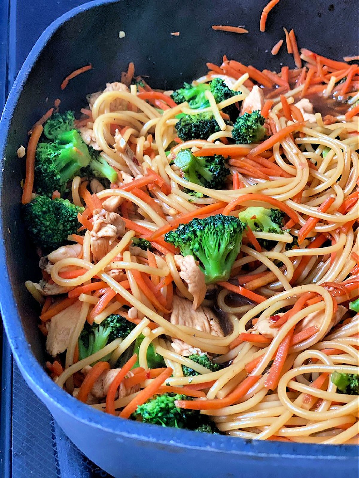 Lo mein with chicken in a black skillet.