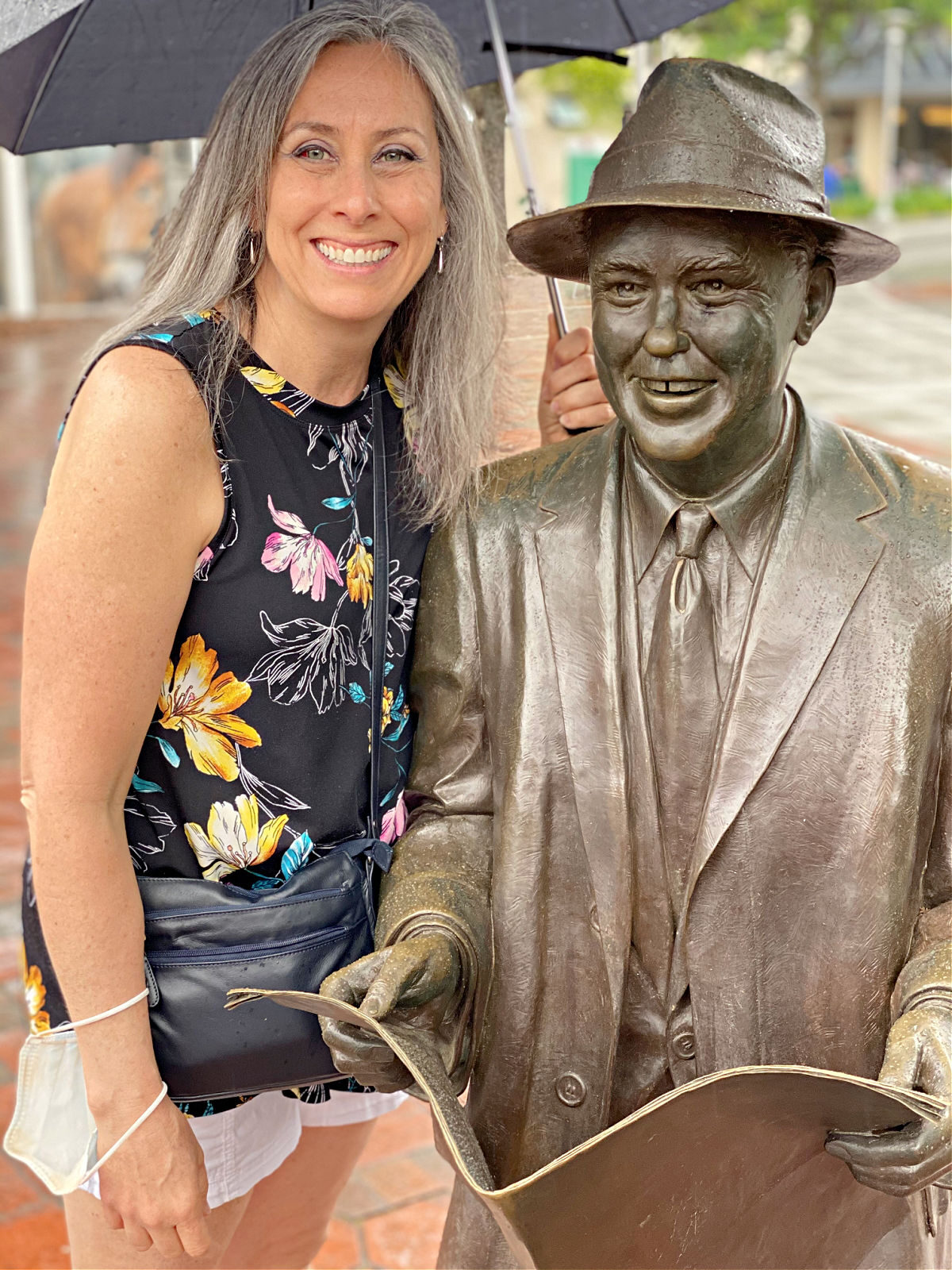 Lynda Self posing with statue of Johnny Mercer underneath an umbrella in Savannah.