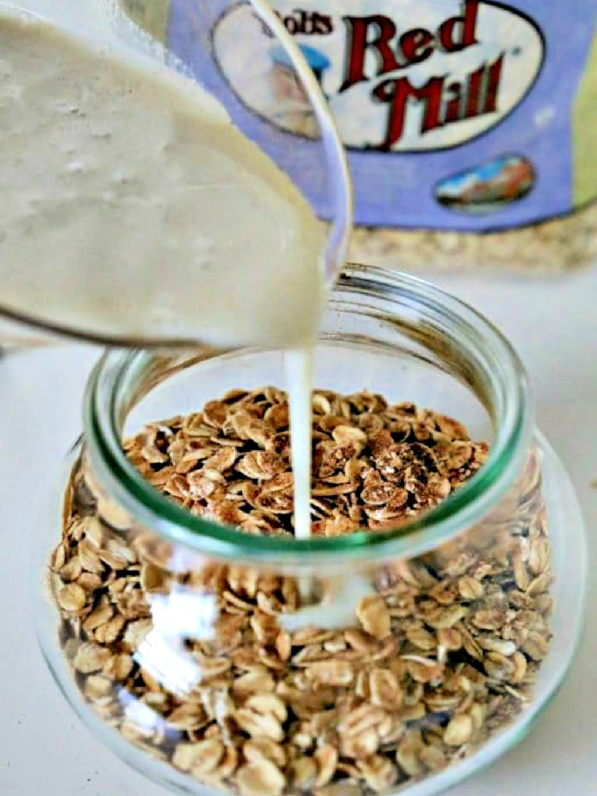 Pouring milk into a glass jar filled with oats.