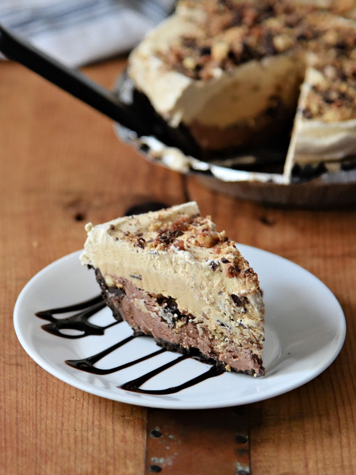 Mexican Chocolate Ice Cream Pie Slice of chocolate ice cream pie on a white plate on a wooden table.
