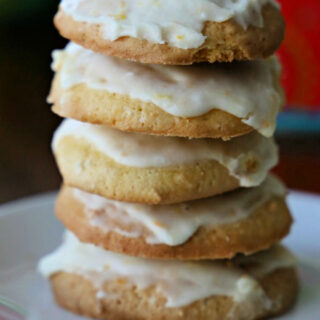 Stack of orange cookies with orange glaze on a white plate.