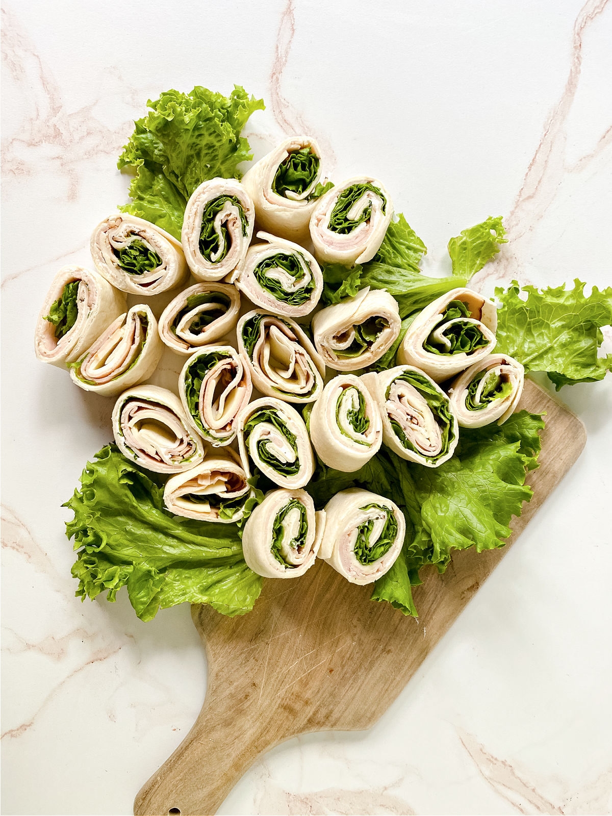 Sliced pinwheel sandwiches and a wooden cutting board.