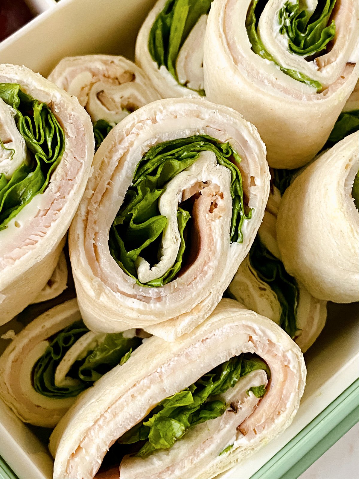 Sliced pinwheel sandwiches in a green container.