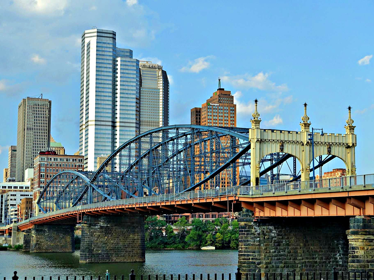 Where To Eat in Pittsburgh Yellow and blue bridge with Pittsburgh skyline in the background.