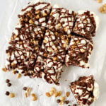 Batch of Rocky Road Brownies and peanuts and chocolate chips on white parchment paper.